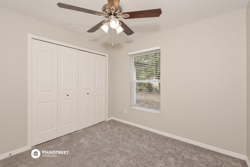 the bedroom has a ceiling fan and two closets