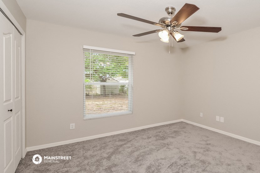 the spacious bedroom has a ceiling fan and a window
