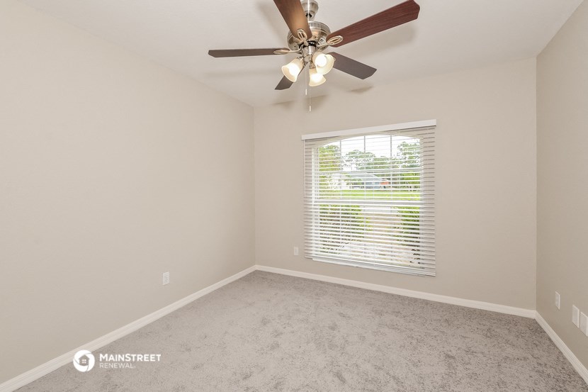 the spacious living room with ceiling fan and window