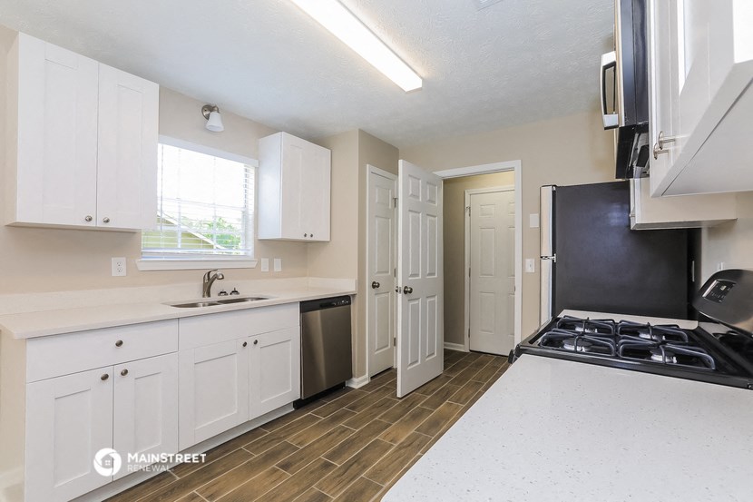 a kitchen with white cabinets and a stove and a sink