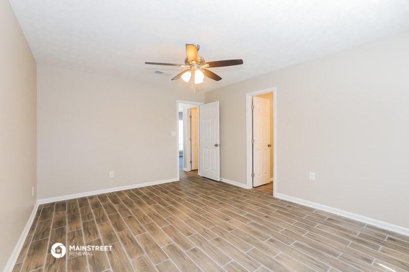 the spacious living room with wood flooring and a ceiling fan