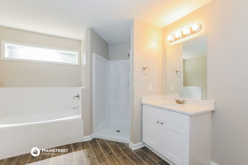 a white bathroom with a tub and a sink and a mirror