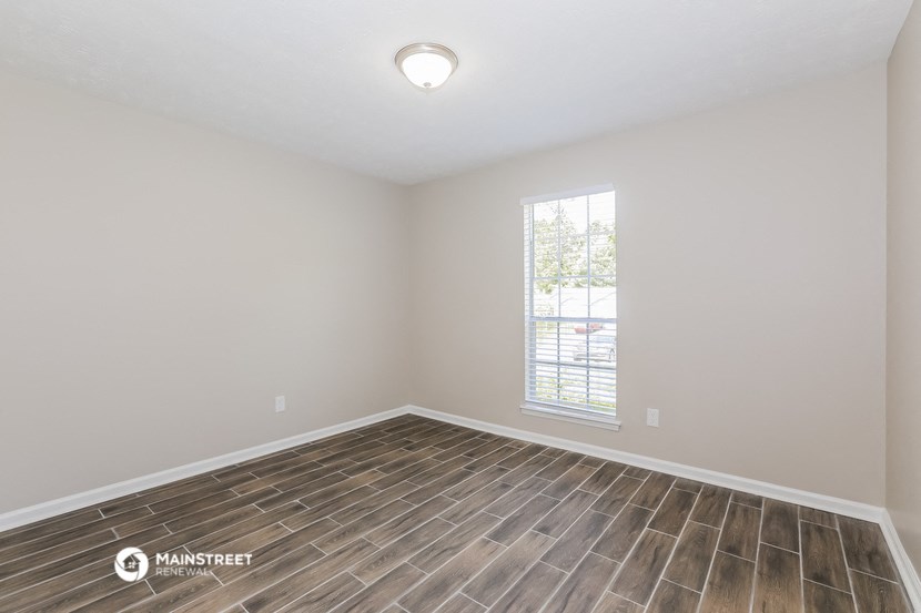 the spacious living room with wood flooring and a window