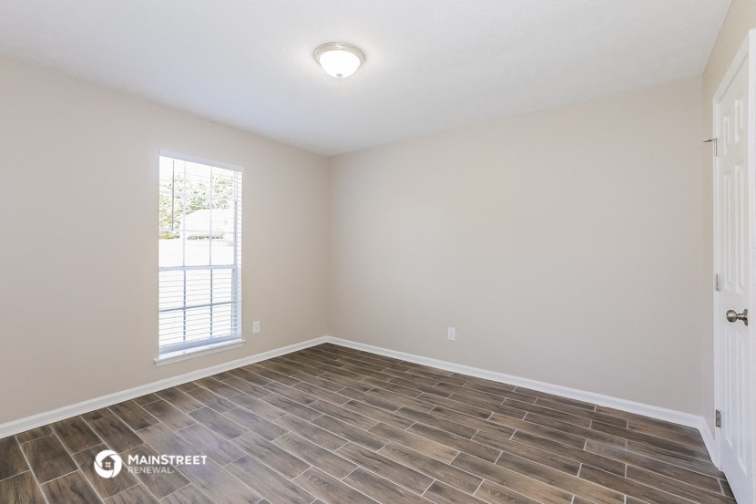 the spacious living room with wood flooring and a window