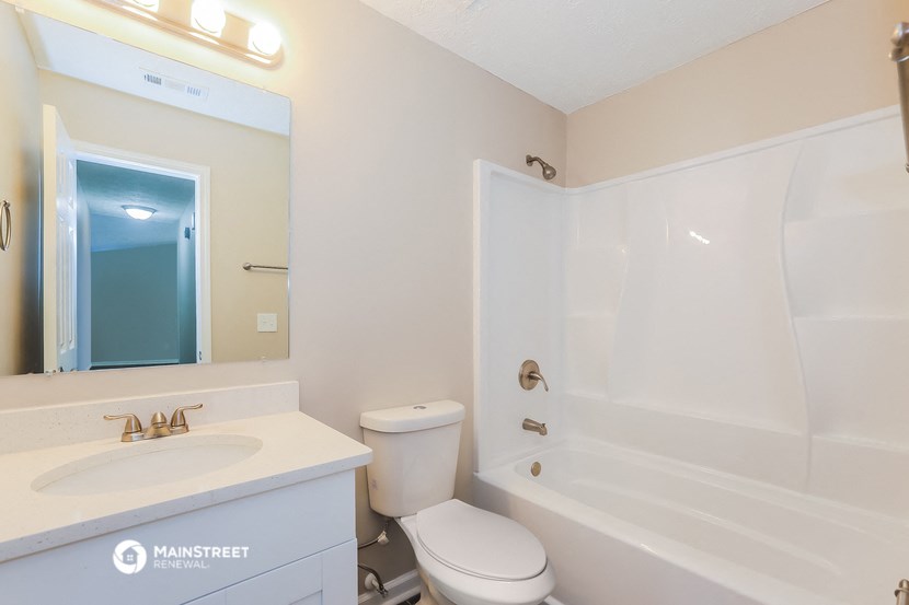 a bathroom with a tub sink and toilet and a mirror