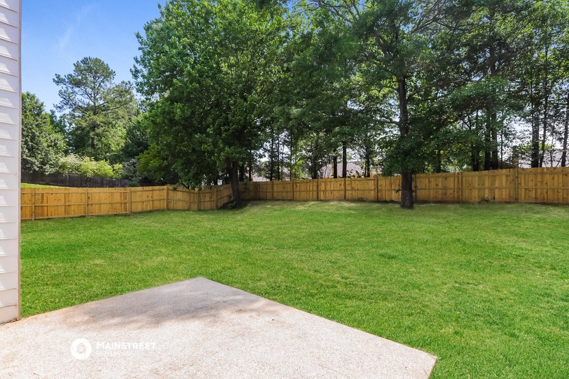 a backyard with a wooden fence and grass and trees