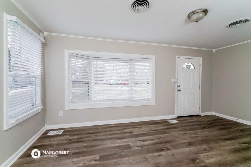 the living room of a home with wood floors and a white door