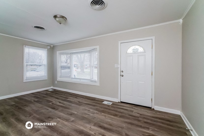 the living room of a rental house with a white door and window