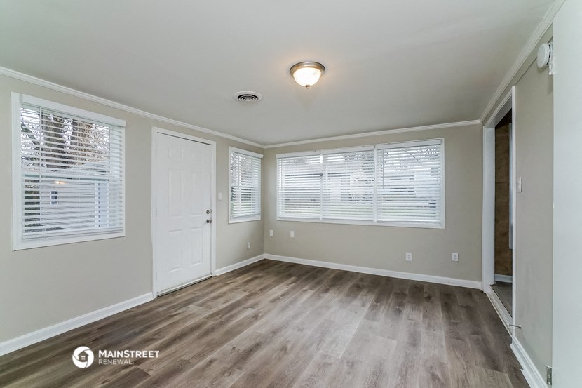 the spacious living room with wood flooring and white walls