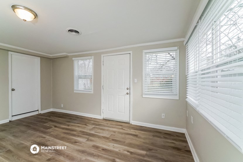 the living room of a home with a large window and a white door