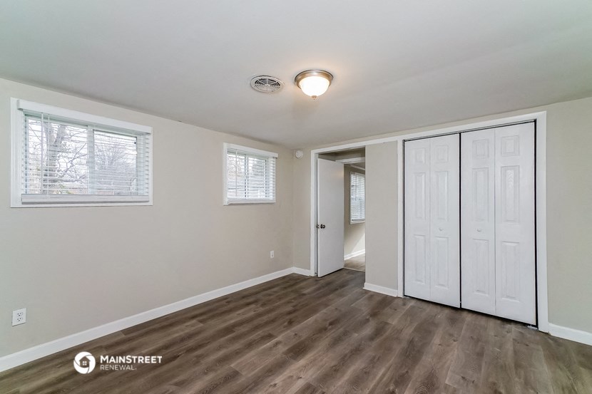 the living room of a home with white walls and wood flooring