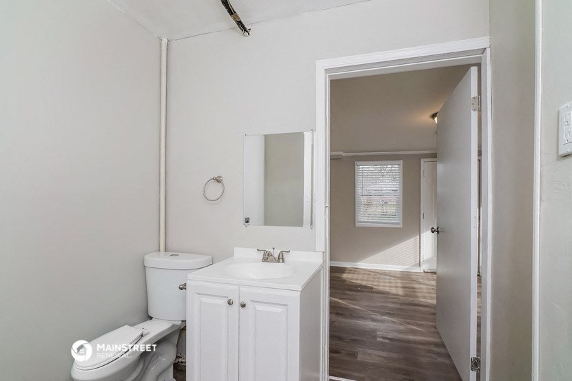a white bathroom with a mirror and a toilet and a sink