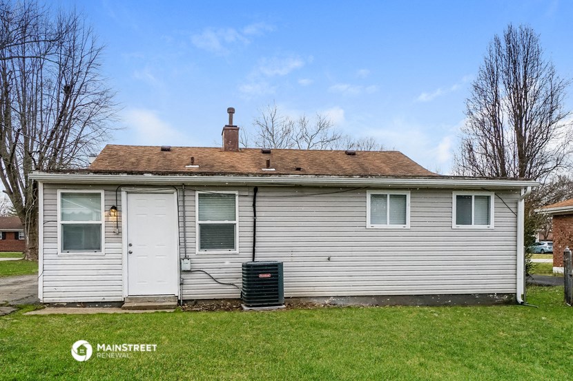 a small white house with two white doors and a black trash can