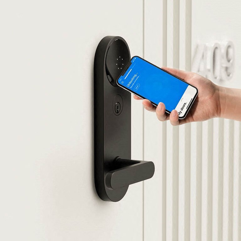 a hand holding a cell phone in a door handle