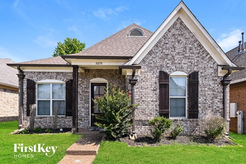 a brick house with black shutters and a lawn