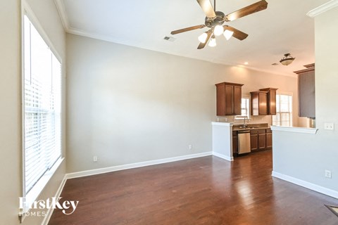 an empty living room and kitchen with a ceiling fan