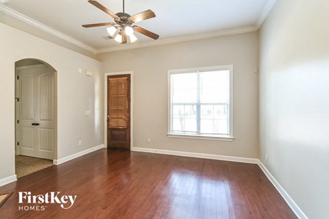 an empty living room with a ceiling fan and a window