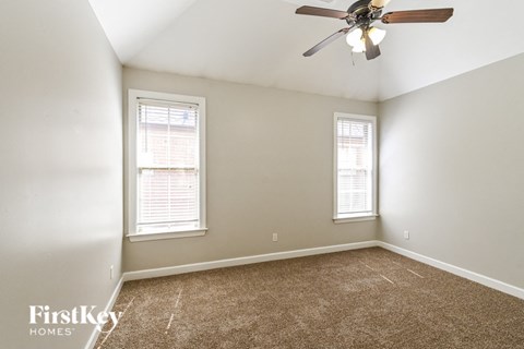 a bedroom with a ceiling fan and two windows