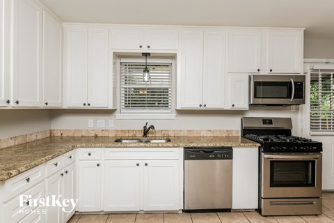 A kitchen with white cabinets and a granite countertop.