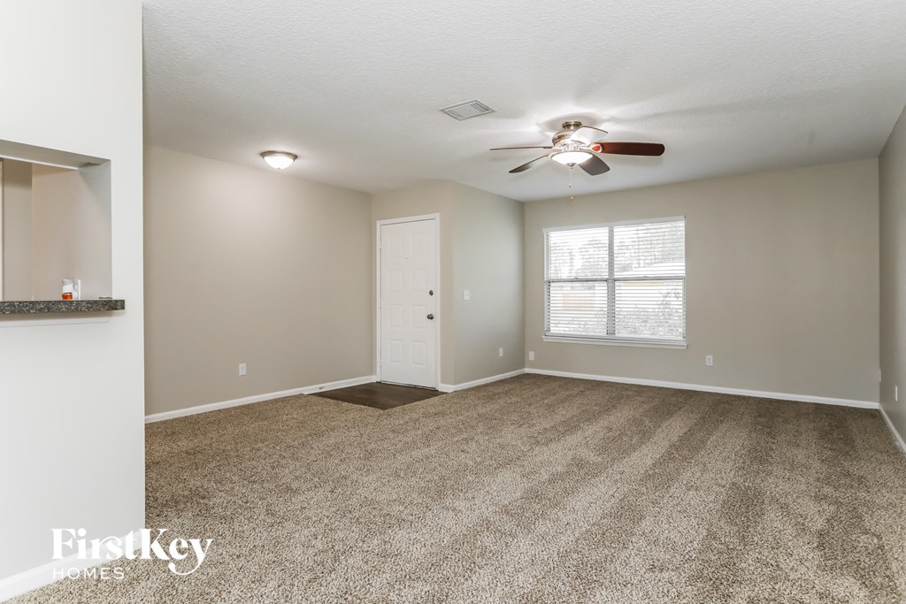 an empty living room with carpet and a ceiling fan