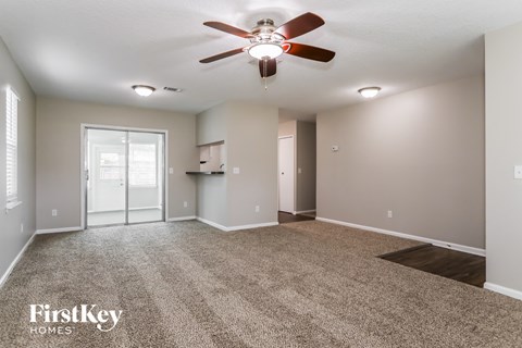 the spacious living room with ceiling fan and carpet