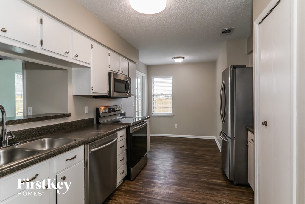 an empty kitchen with stainless steel appliances and white cabinets
