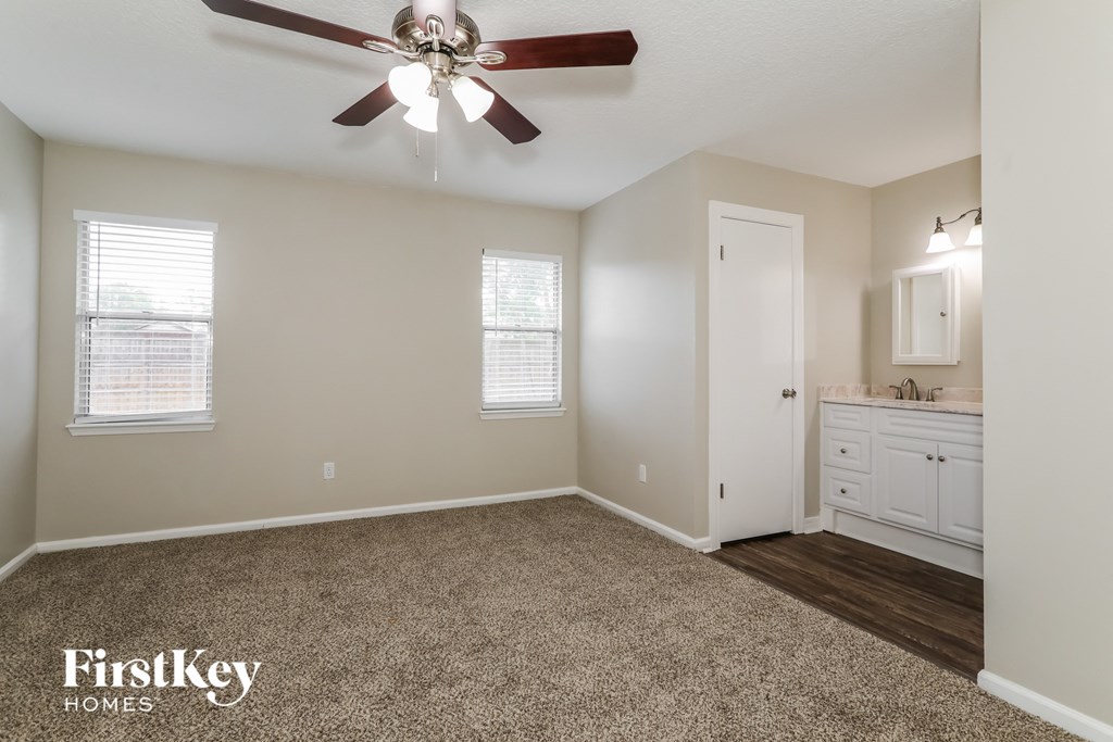 a bedroom with a ceiling fan and a white bathroom