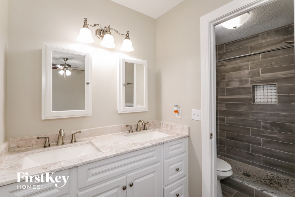 a bathroom with two sinks and a shower and a mirror