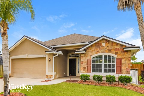 a beige house with a garage and palm trees