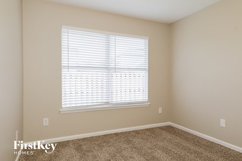 a bedroom with a large window and a carpeted floor