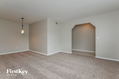 a spacious living room with carpet and grey walls