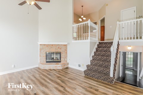 A living room with a fireplace and a staircase.