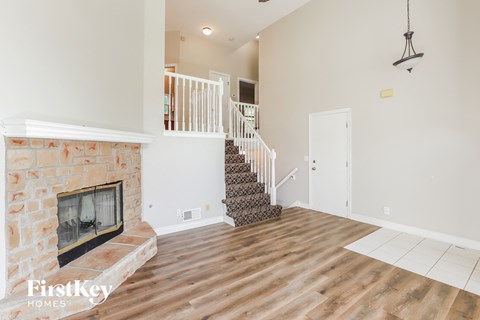 A living room with a fireplace and a staircase.