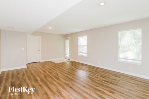 A spacious room with wooden flooring and white walls.