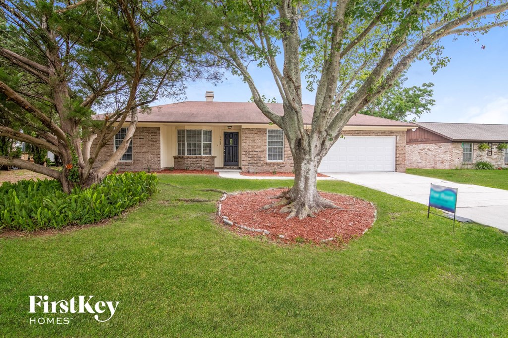 A tree in a front yard with a sign that says FirstKey Homes.