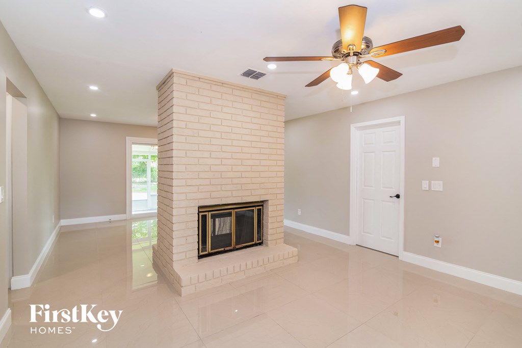 A living room with a fireplace and a ceiling fan.