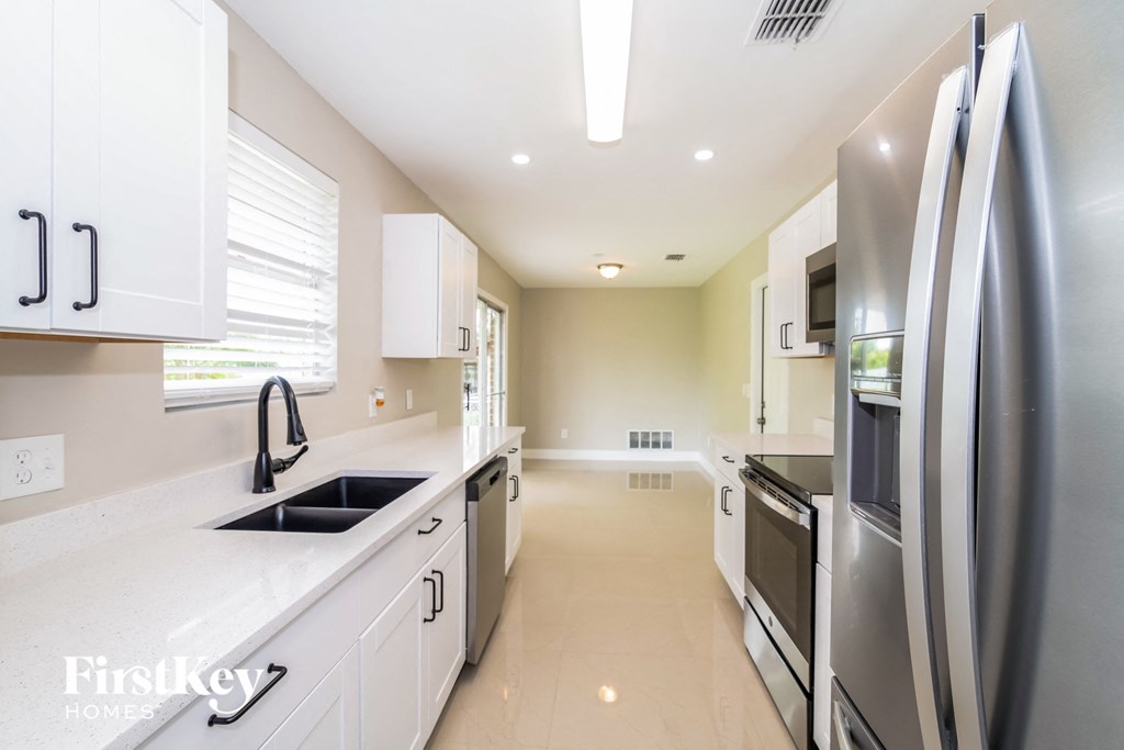 A modern kitchen with white cabinets and stainless steel appliances.