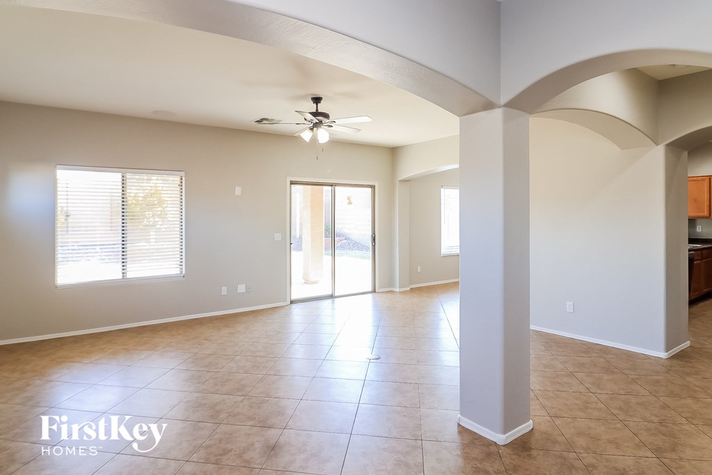 an empty living room with a ceiling fan and a door to a patio