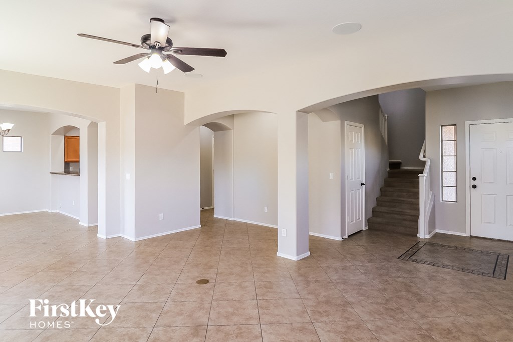 an empty living room and hallway with a ceiling fan