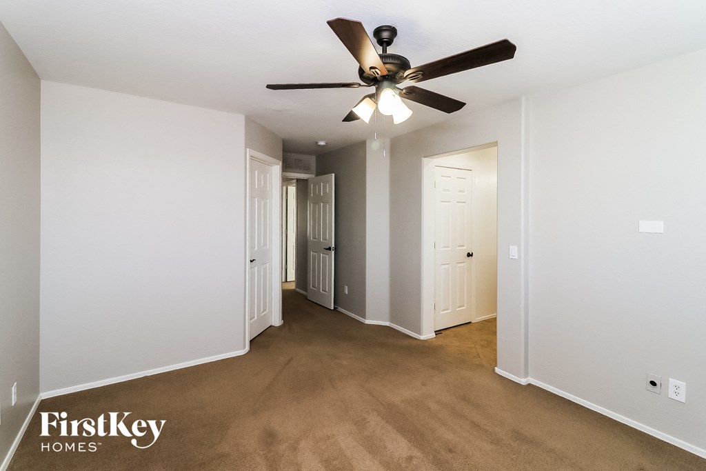 an empty living room with a ceiling fan and white walls