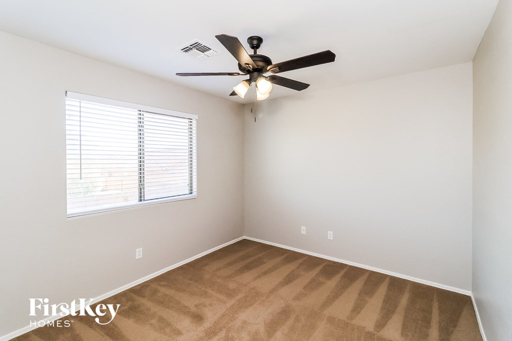 an empty room with a ceiling fan and a window