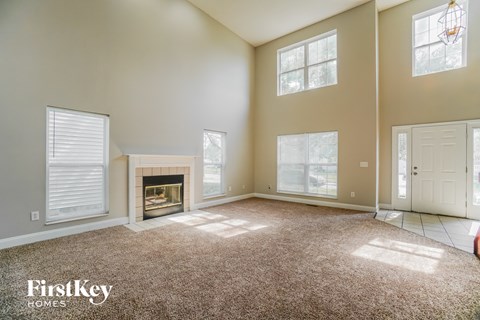an empty living room with a fireplace and windows