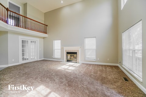 an empty living room with a fireplace and a balcony