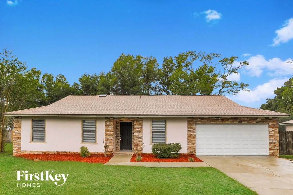 a small brick house with a garage and a lawn