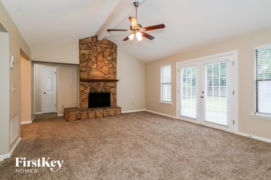 an empty living room with a fireplace and a ceiling fan
