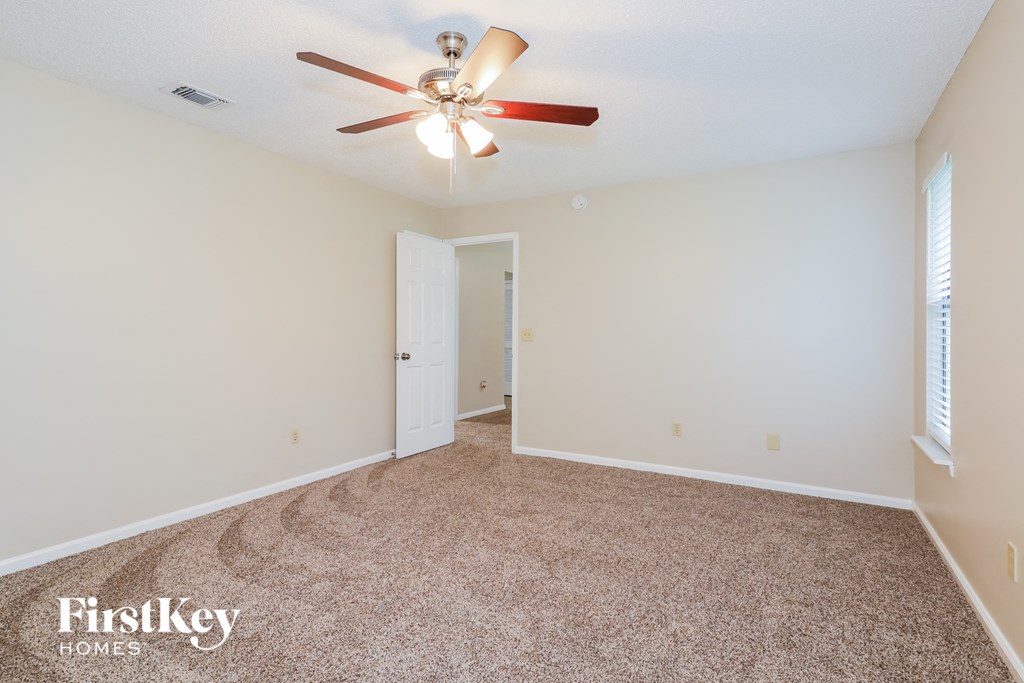 a spacious living room with carpet and a ceiling fan
