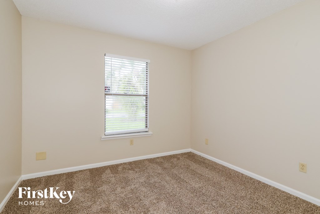a spacious room with carpet and a window