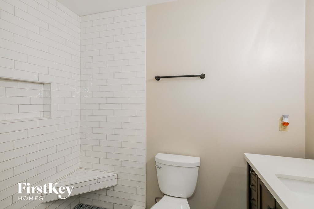 a white bathroom with white subway tiles and a toilet