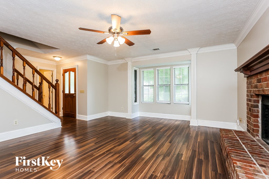 an empty living room with a fireplace and a ceiling fan