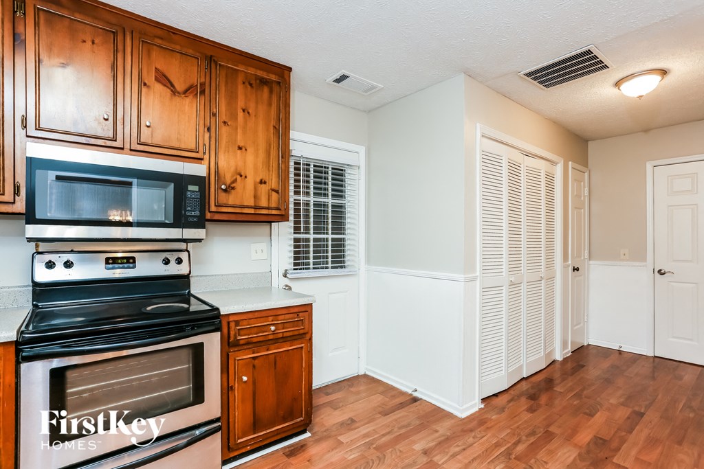 a kitchen with a stove and a microwave and wooden cabinets